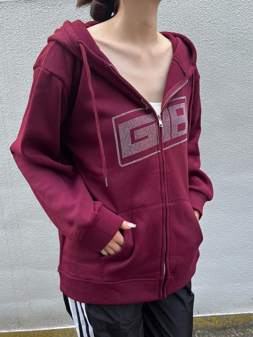 レッド系のパーカー、ブラック系のスウェットパンツを着用したレディースの秋コーディネートの2枚目の写真