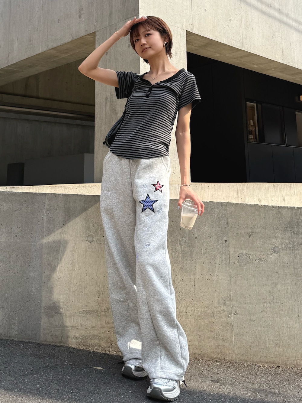 グレー系のスウェットパンツ、ブラック系のショルダーバッグ、シルバー系のスニーカーを着用したレディースの夏コーディネートの2枚目の写真