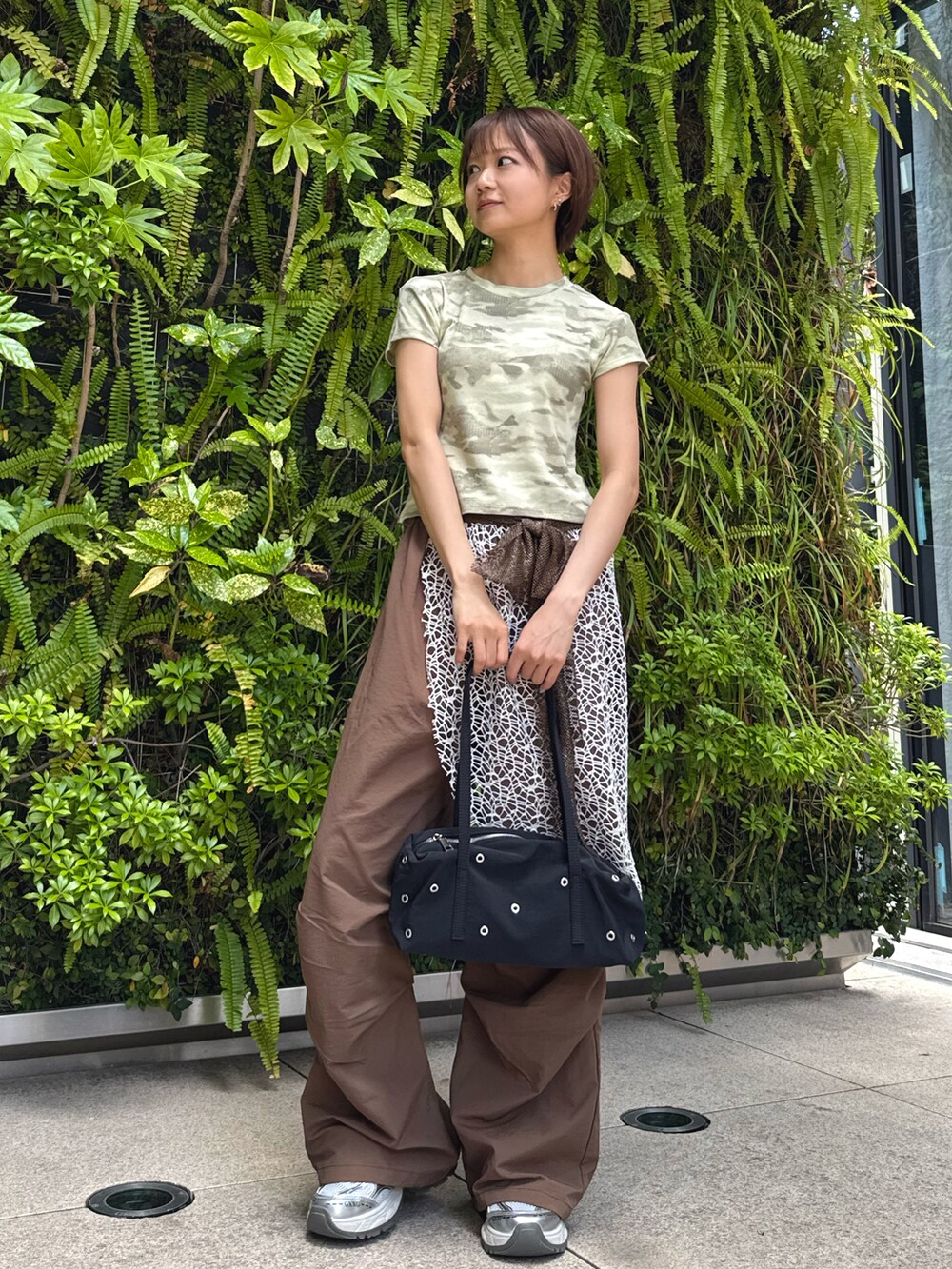 グリーン系のTシャツ/カットソー、ブラウン系のその他パンツ、ブラック系のショルダーバッグを着用したレディースの春コーディネートの2枚目の写真