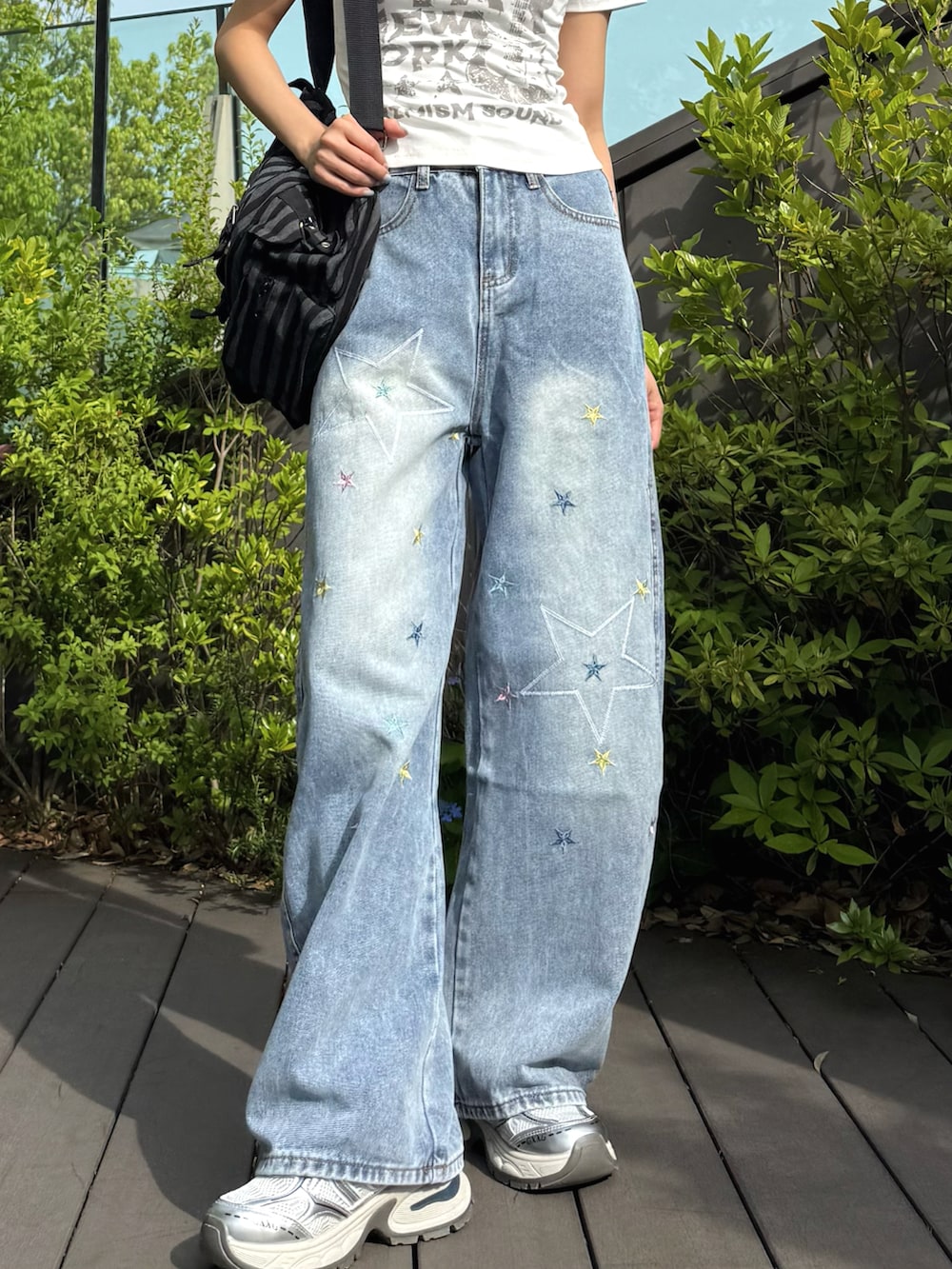 ホワイト系のTシャツ/カットソー、ブルー系のデニムパンツ、ブラック系のバックパック/リュックを着用したレディースの春コーディネートの3枚目の写真