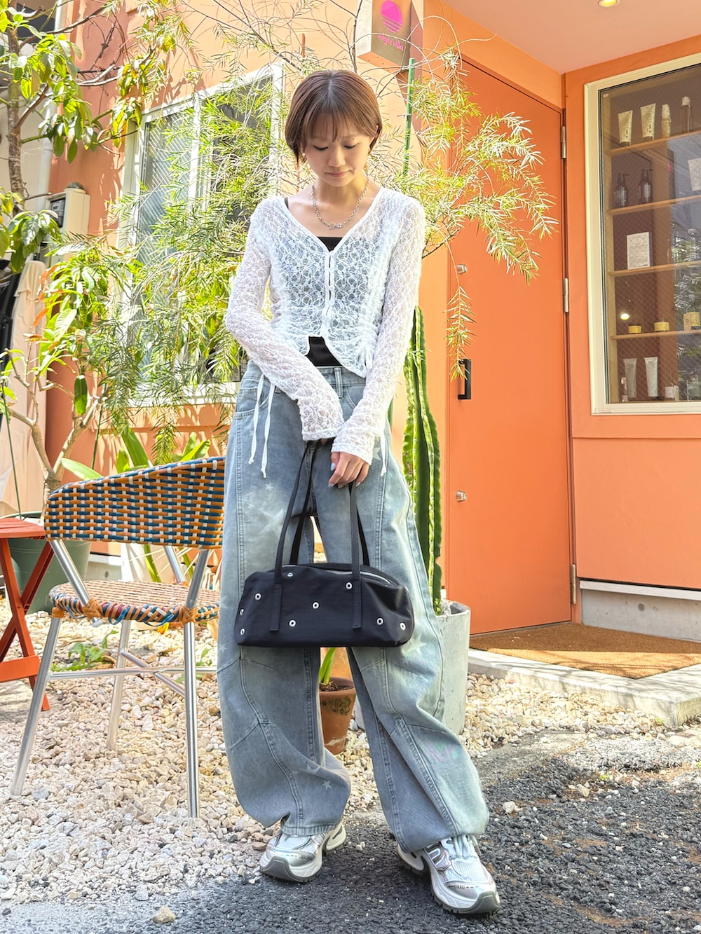 ホワイト系のカーディガン/ボレロ、ブルー系のデニムパンツ、ブラック系のショルダーバッグを着用したレディースの春コーディネートの2枚目の写真