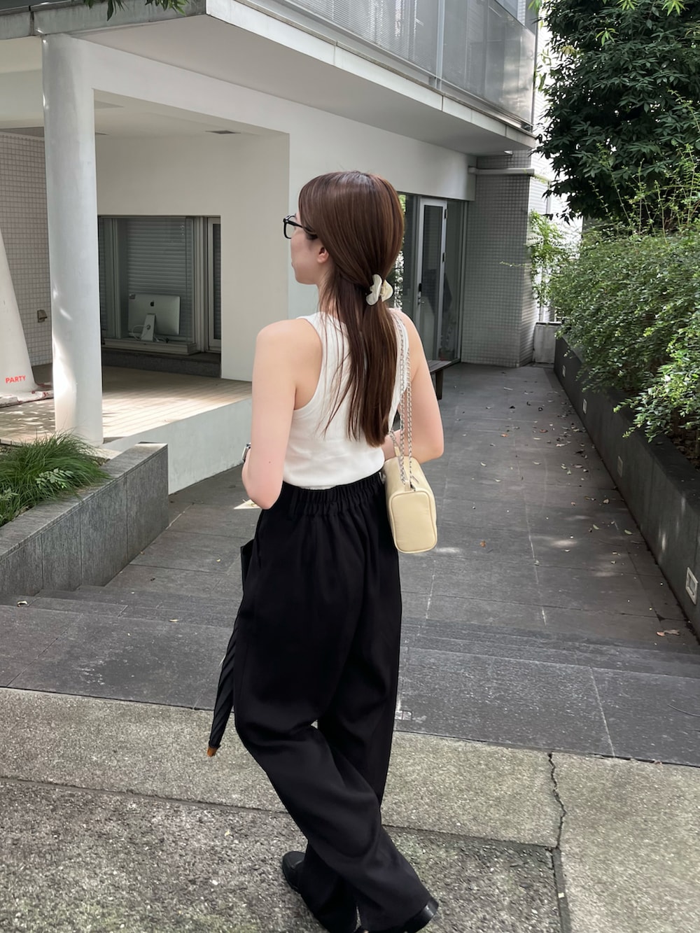 ホワイト系のタンクトップ、ブラック系のパンツ、ホワイト系のバッグを着用したレディースの夏コーディネートの2枚目の写真