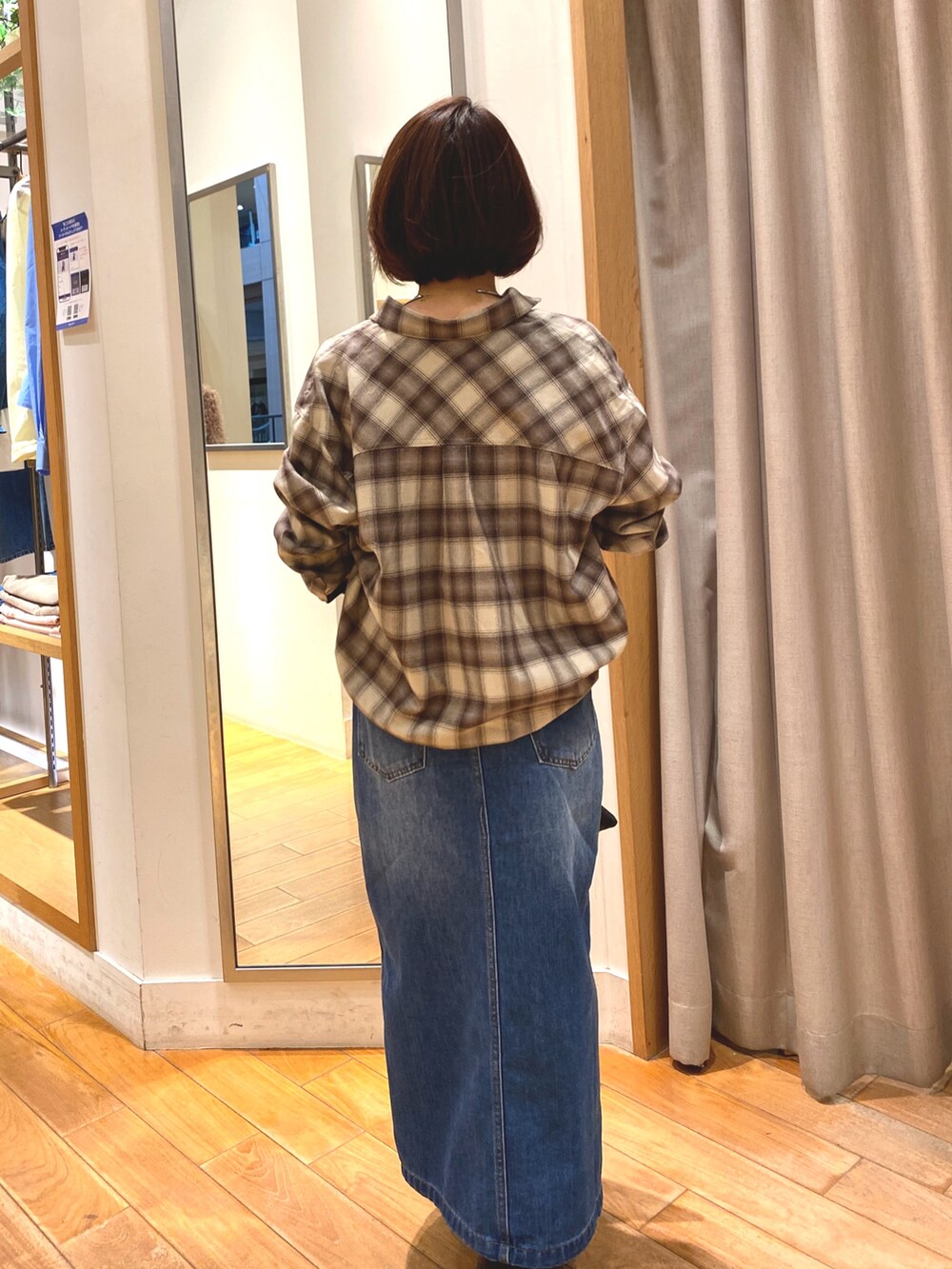 ブラウン系のシャツ/ブラウス、ブルー系のデニムスカート、ブラック系のショルダーバッグを着用したレディースの秋コーディネートの6枚目の写真