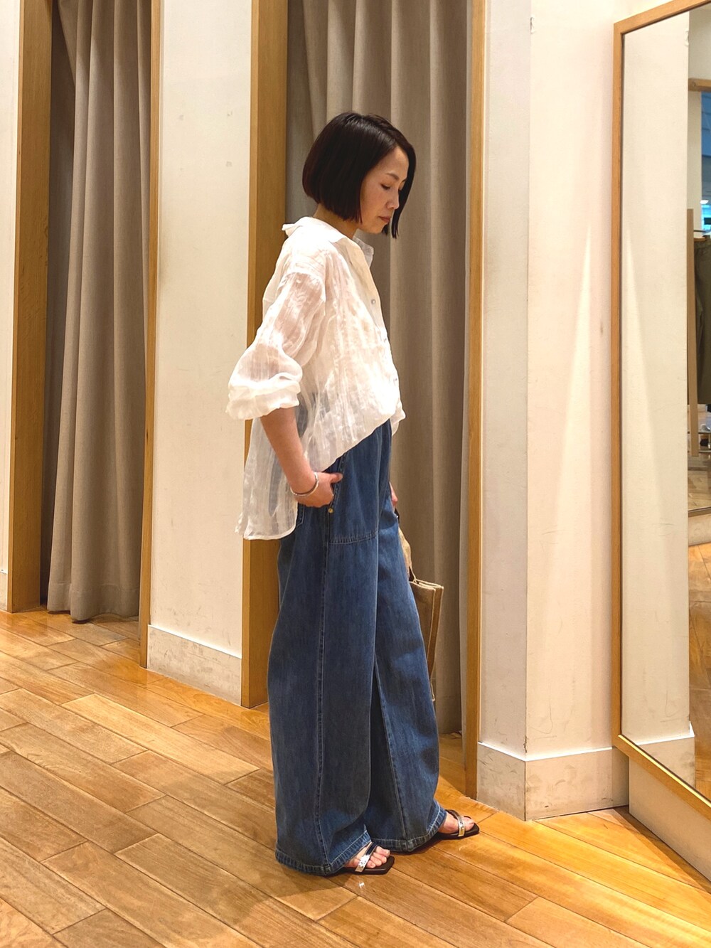 ブルー系のデニムパンツ、ベージュ系のトートバッグ、ホワイト系のシャツ/ブラウスを着用したレディースの春コーディネートの6枚目の写真