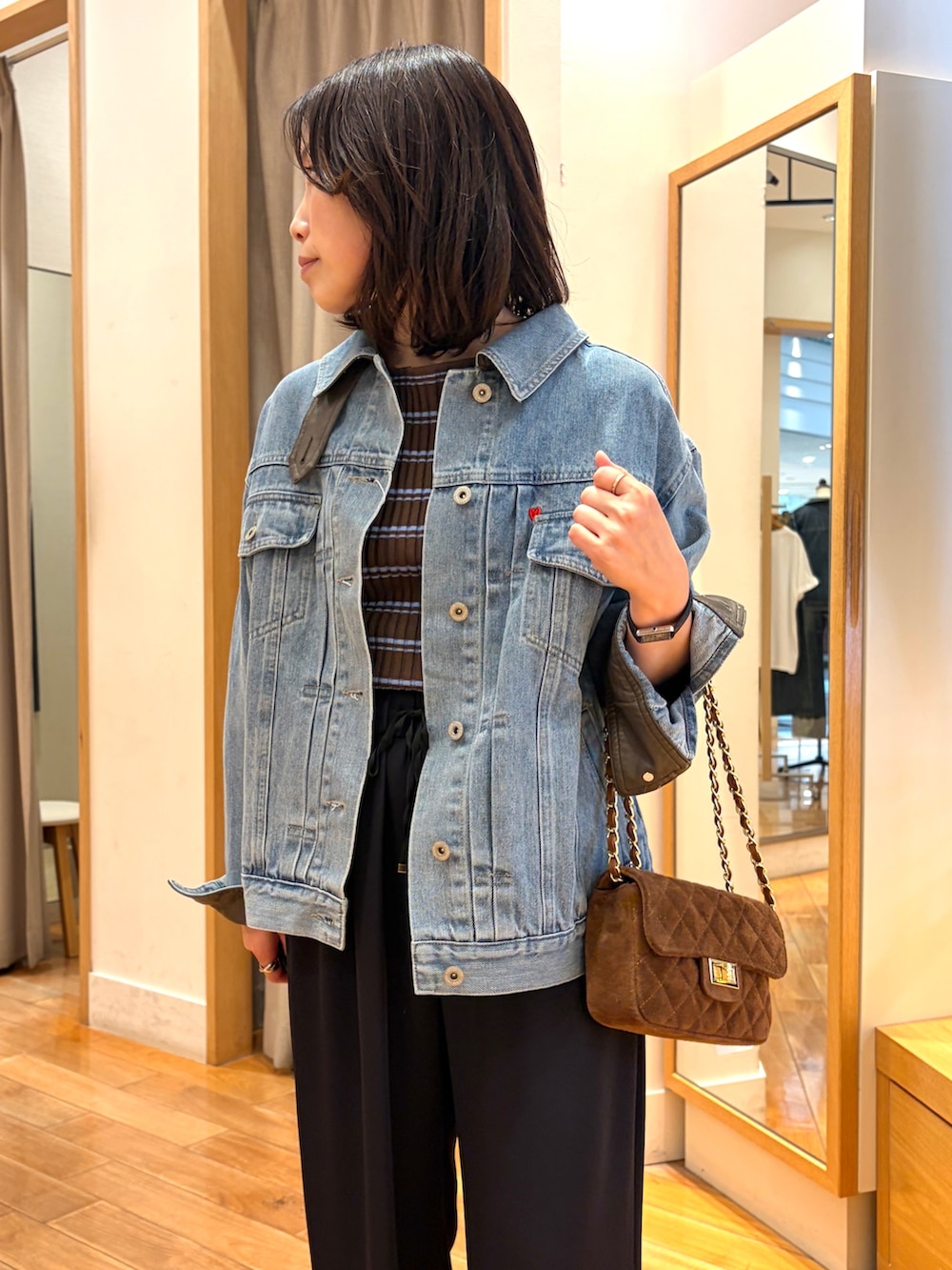 ブラック系のその他パンツ、ブルー系のデニムジャケット、ブラウン系のニット/セーターを着用したレディースの夏コーディネートの3枚目の写真
