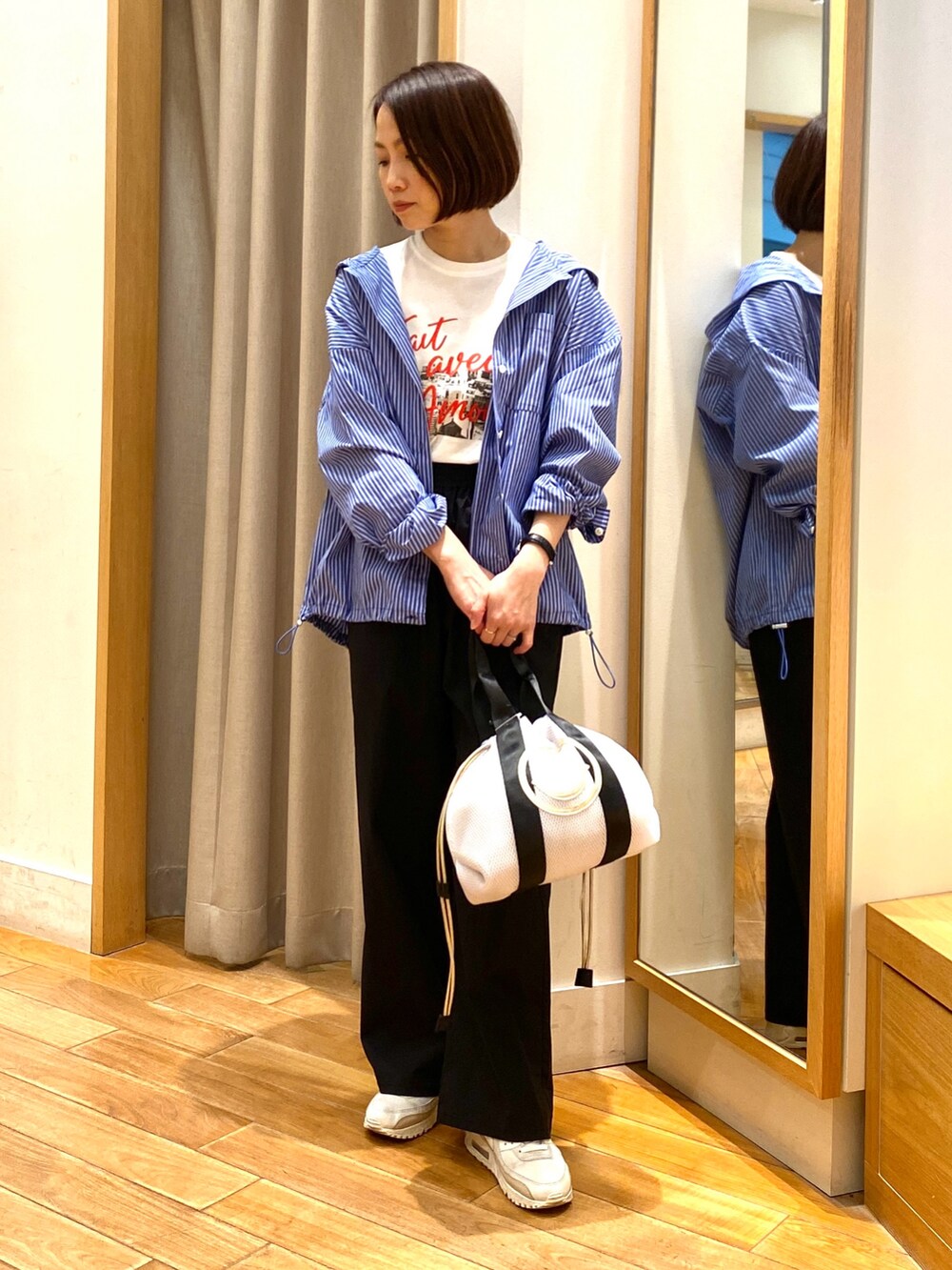 ホワイト系のトートバッグ、ブルー系のシャツ/ブラウス、ホワイト系のTシャツ/カットソーを着用したレディースの春コーディネートの2枚目の写真