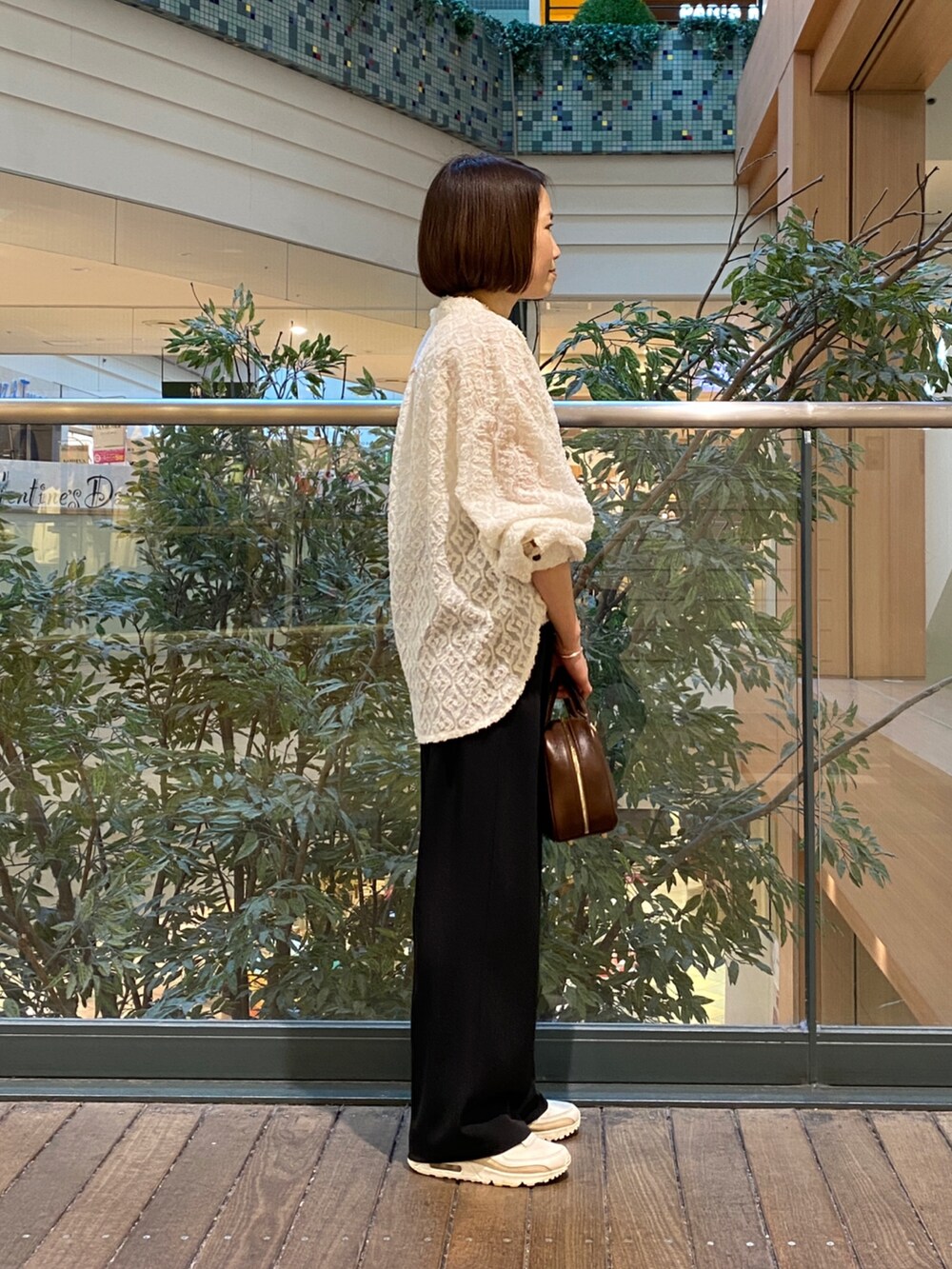 ホワイト系のシャツ/ブラウス、ブラック系のスラックス、ブラウン系のハンドバッグを着用したレディースの冬コーディネートの4枚目の写真