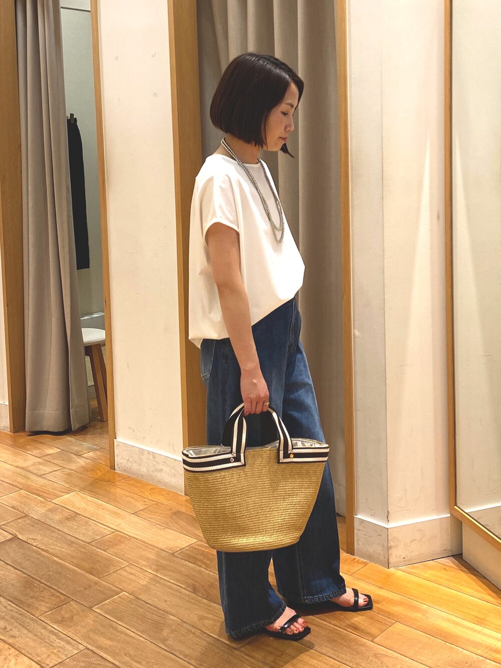 ブルー系のデニムパンツ、ホワイト系のTシャツ/カットソー、ベージュ系のかごバッグを着用したレディースの夏コーディネートの6枚目の写真