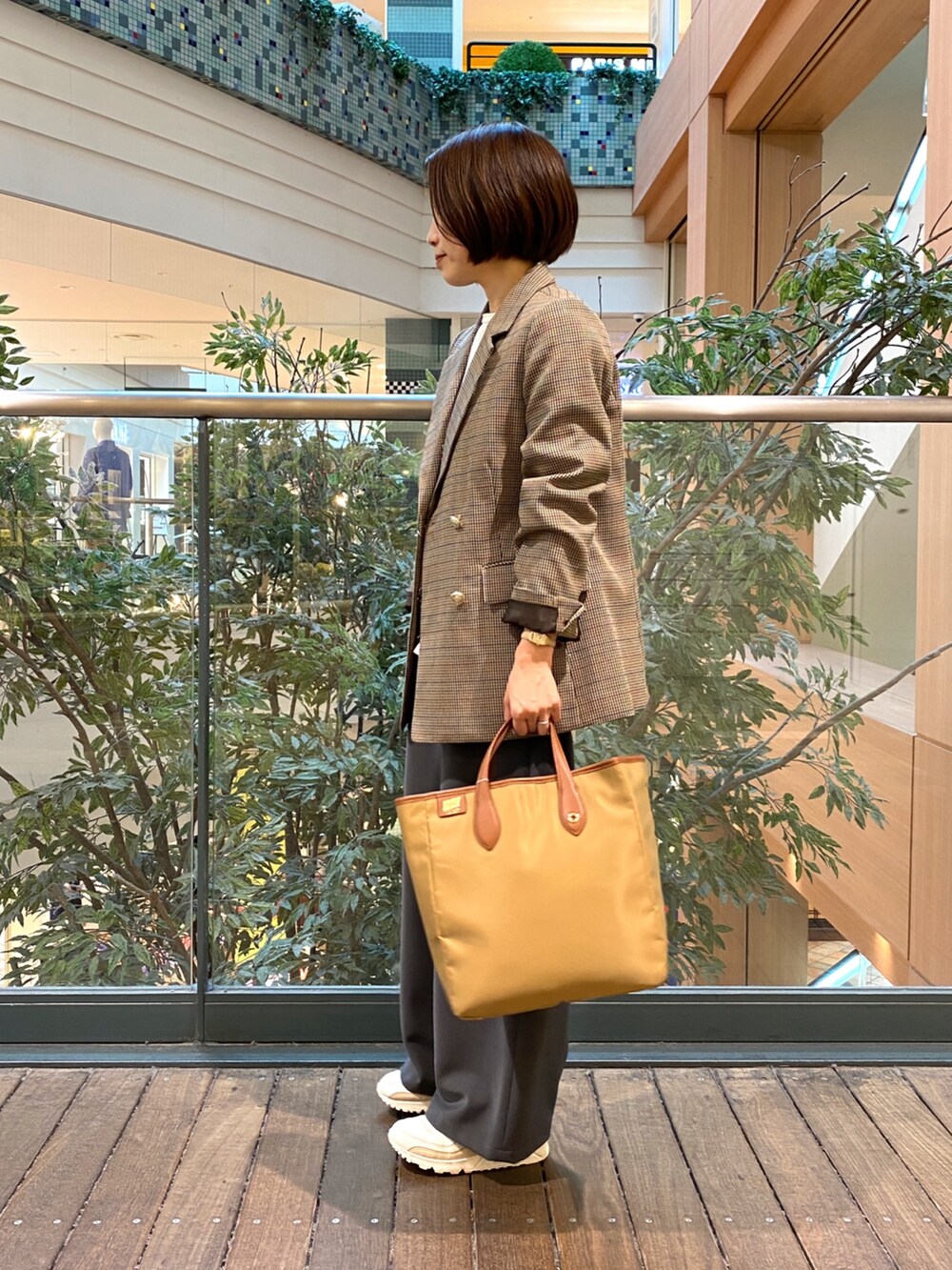 ベージュ系のテーラードジャケット、ホワイト系のベスト、イエロー系のショルダーバッグを着用したレディースの秋コーディネートの4枚目の写真