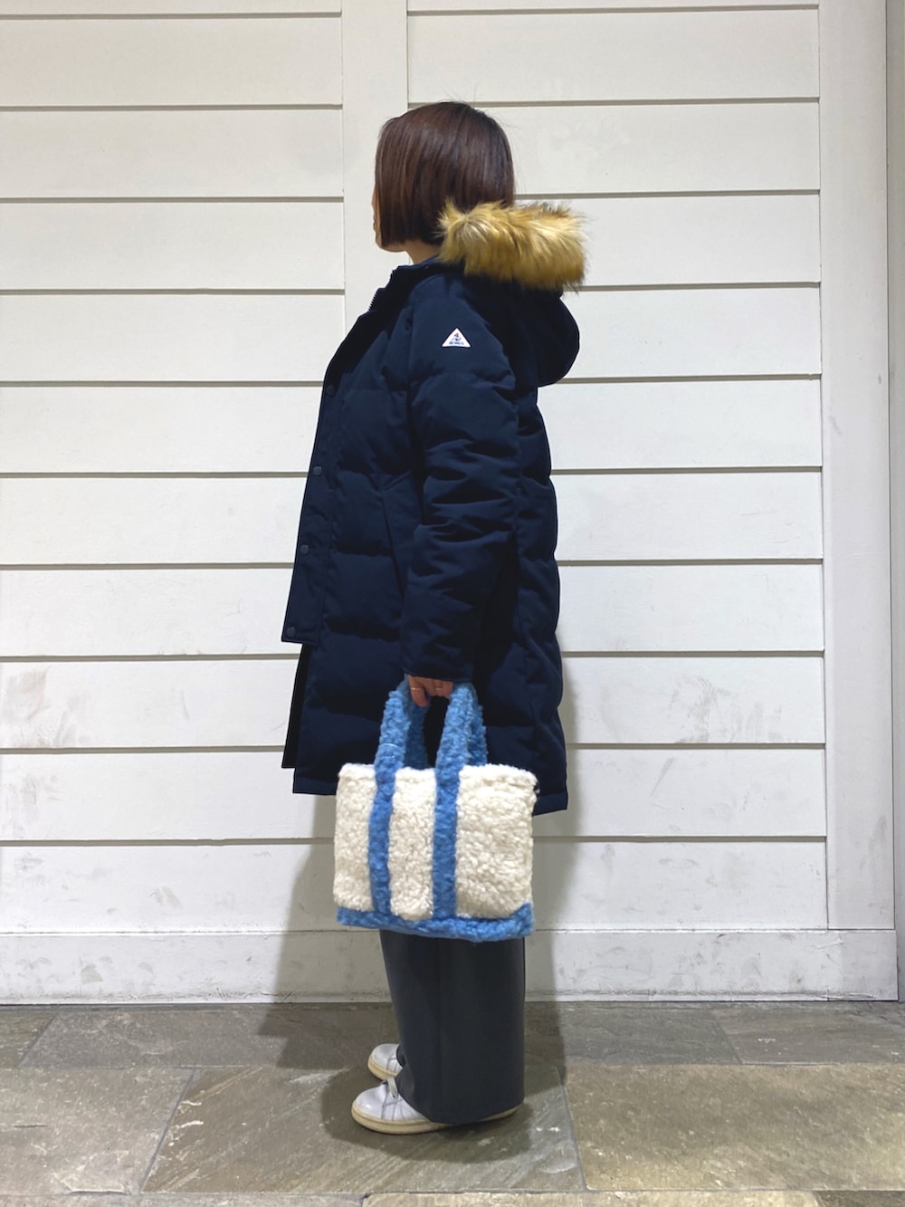 ブルー系のダウンジャケット/コート、ホワイト系のニット/セーター、ブルー系のトートバッグを着用したレディースの冬コーディネートの4枚目の写真