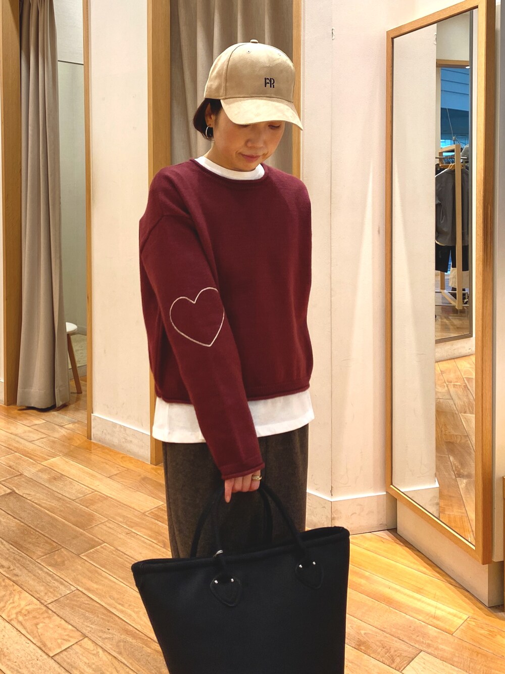 レッド系のニット/セーター、ブラウン系のスカート、ホワイト系のTシャツ/カットソーを着用したレディースの秋コーディネートの2枚目の写真