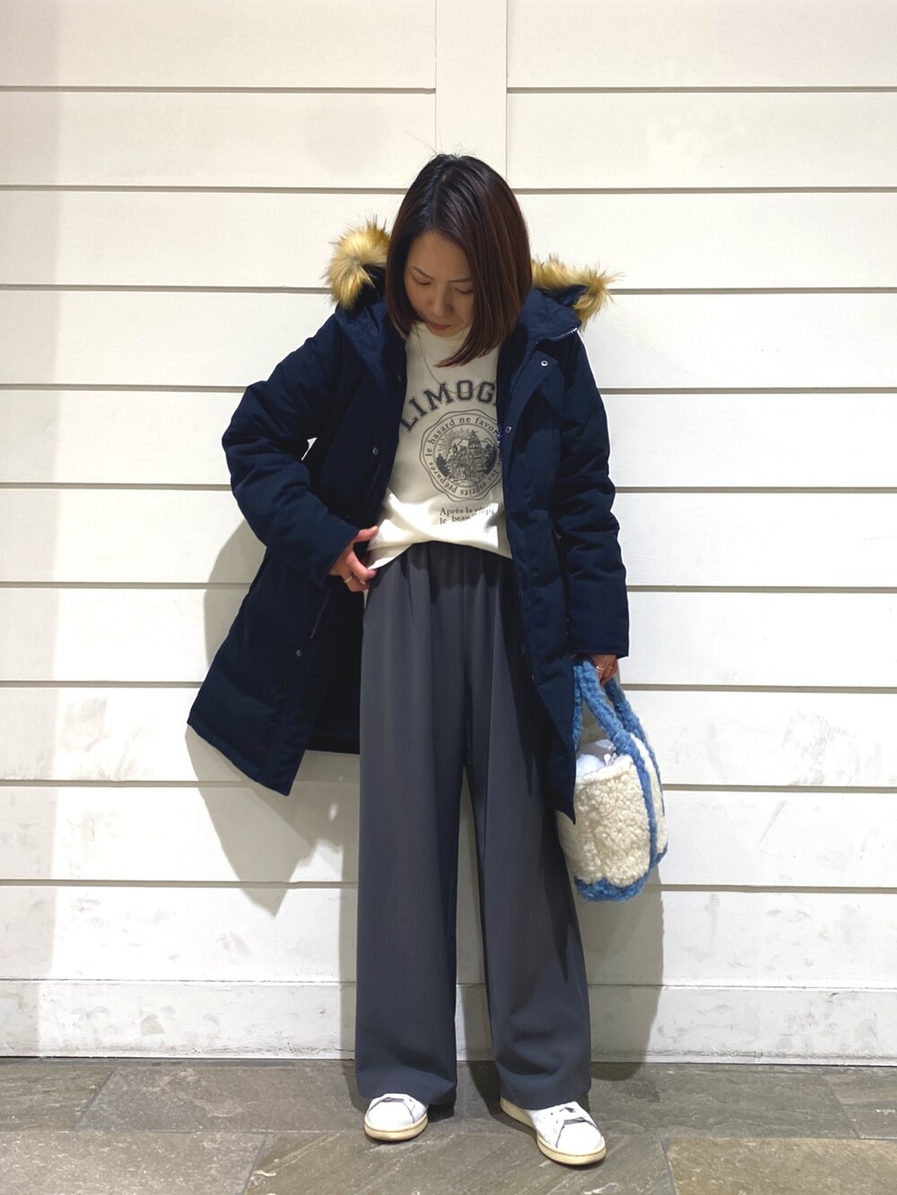 ブルー系のダウンジャケット/コート、ホワイト系のニット/セーター、ブルー系のトートバッグを着用したレディースの冬コーディネートの3枚目の写真