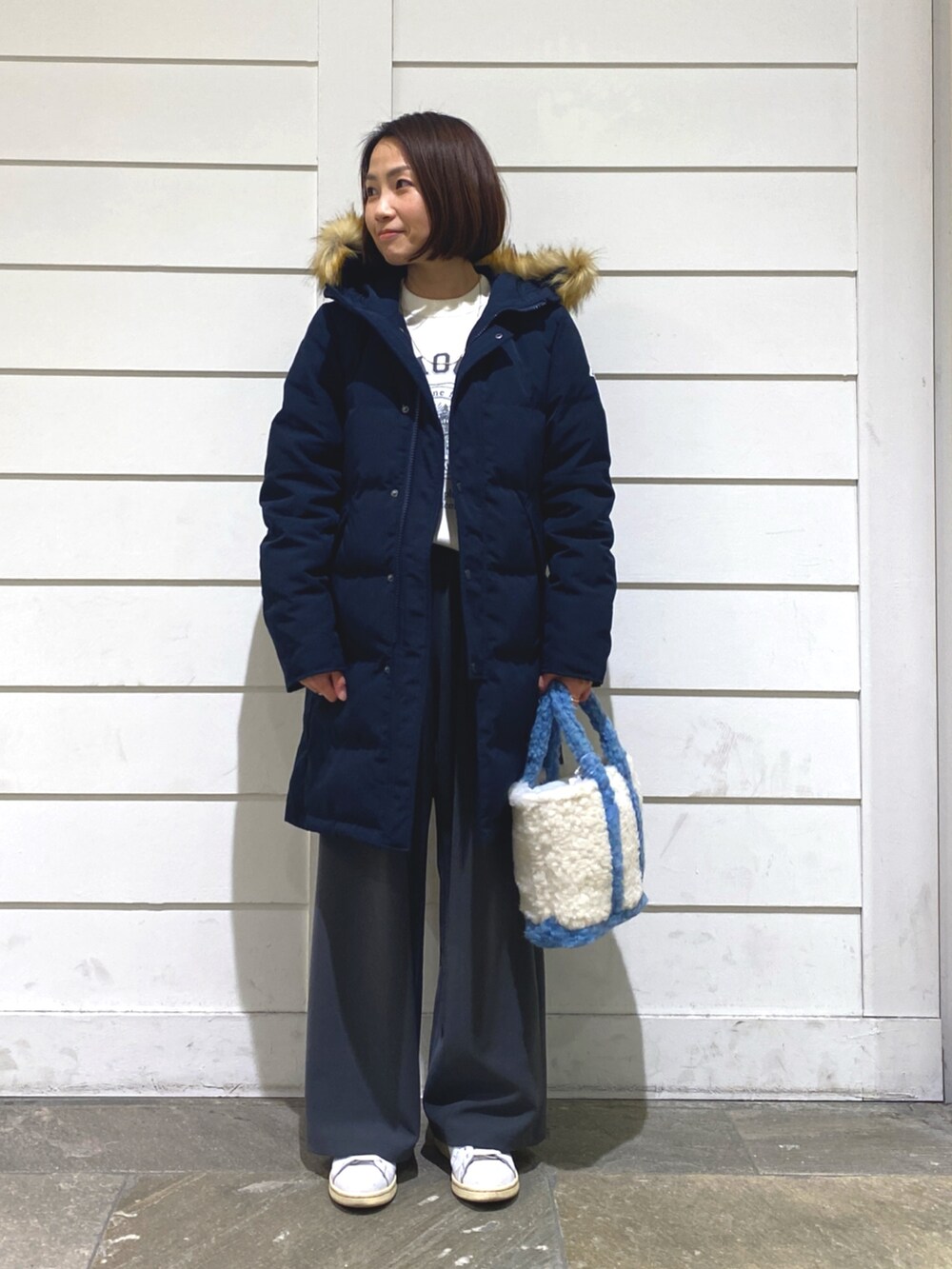 ブルー系のダウンジャケット/コート、ホワイト系のニット/セーター、ブルー系のトートバッグを着用したレディースの冬コーディネートの2枚目の写真