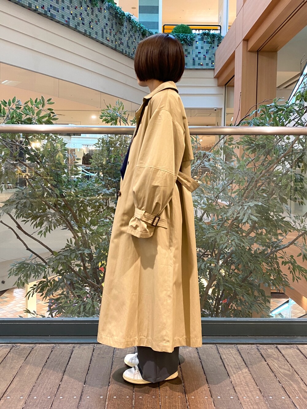 ベージュ系のトレンチコート、ブルー系のニット/セーター、グレー系のその他パンツを着用したレディースの秋コーディネートの4枚目の写真