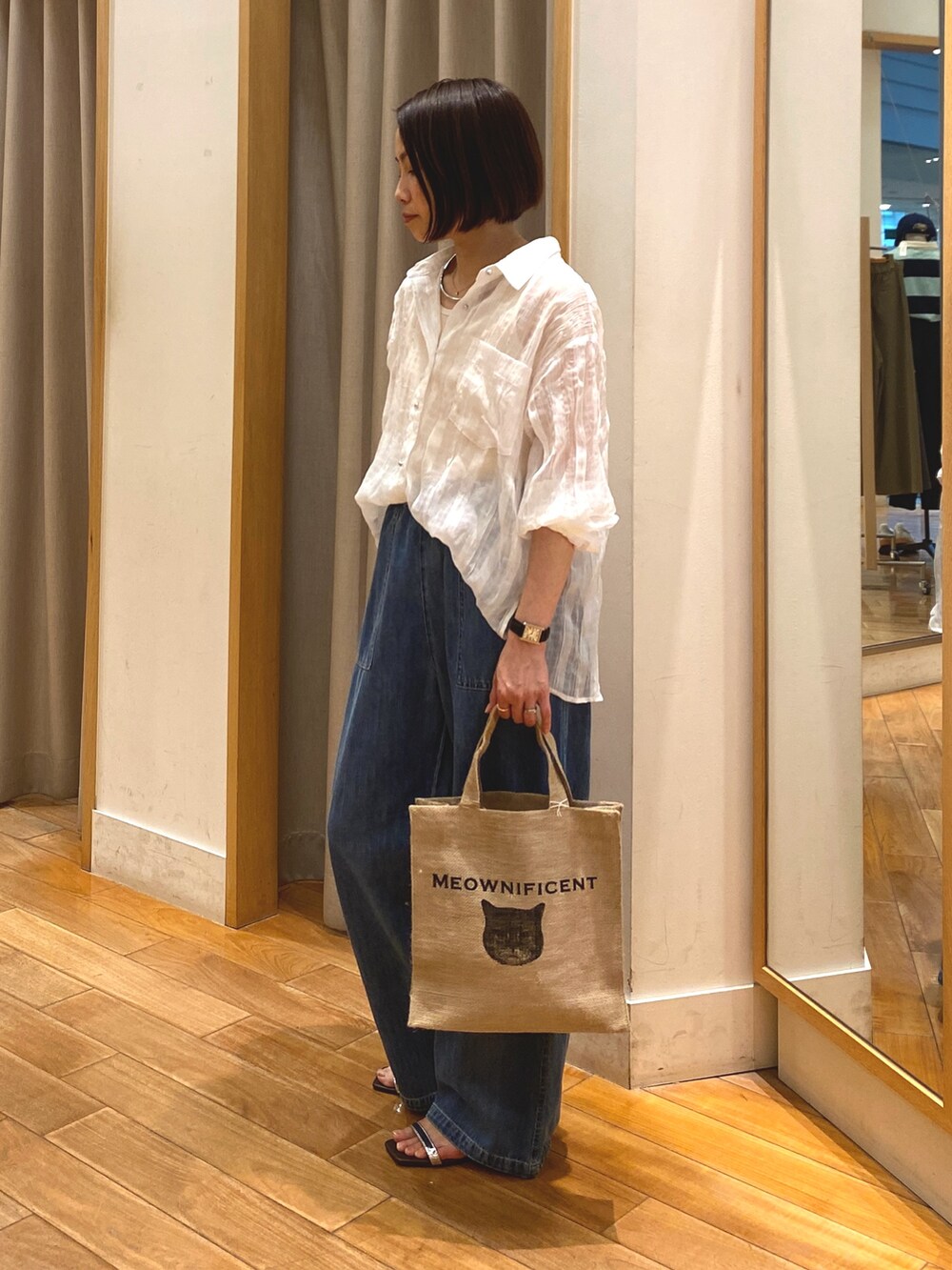 ブルー系のデニムパンツ、ベージュ系のトートバッグ、ホワイト系のシャツ/ブラウスを着用したレディースの春コーディネートの3枚目の写真