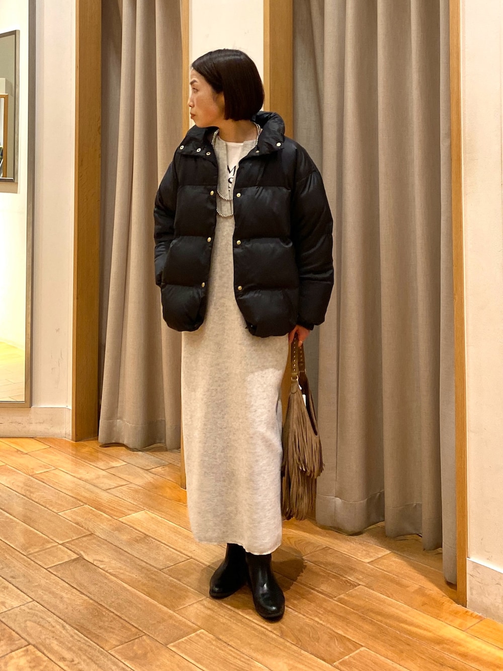 ベージュ系のショルダーバッグ、ブラック系のダウンジャケット/コート、ホワイト系のTシャツ/カットソーを着用したレディースの秋コーディネートの4枚目の写真