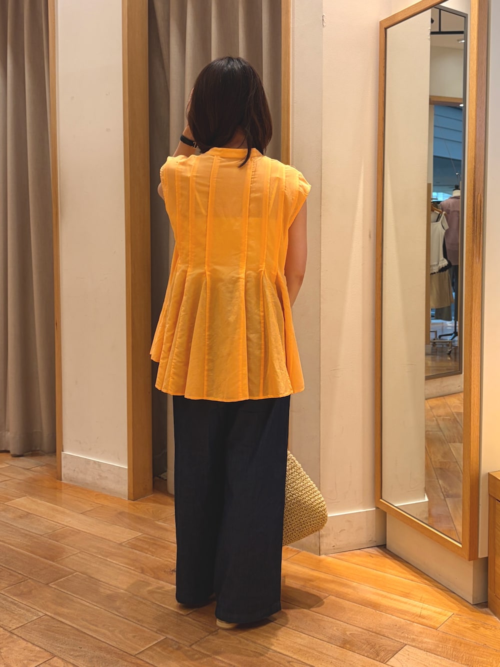 オレンジ系のシャツ/ブラウス、ブルー系のデニムパンツ、ベージュ系のトートバッグを着用したレディースの夏コーディネートの9枚目の写真