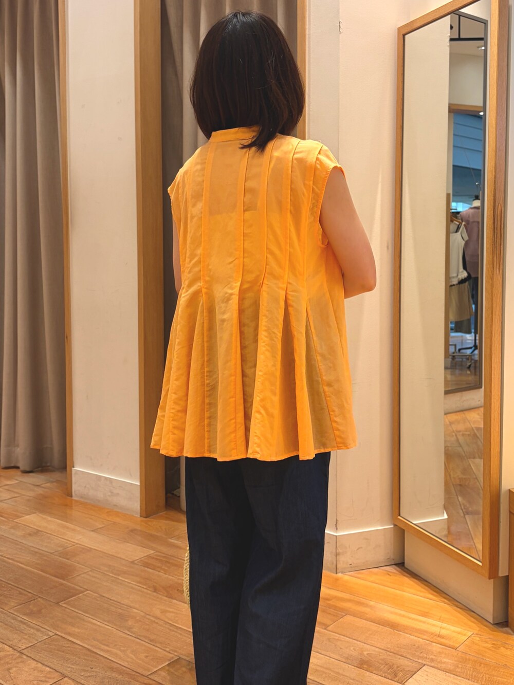 オレンジ系のシャツ/ブラウス、ブルー系のデニムパンツ、ベージュ系のトートバッグを着用したレディースの夏コーディネートの4枚目の写真