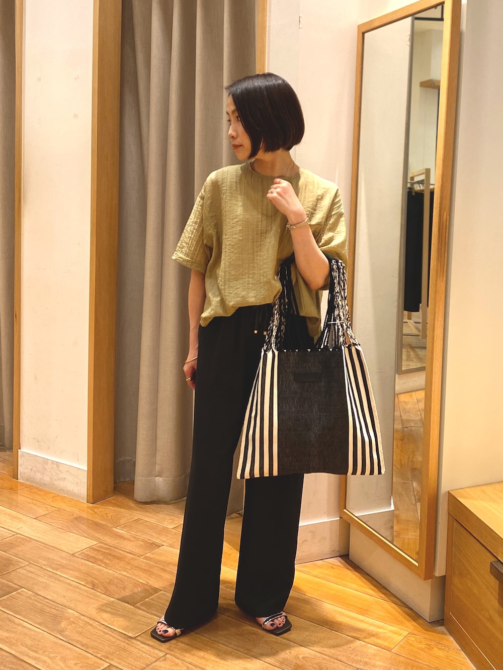 イエロー系のシャツ/ブラウス、グレー系のその他パンツ、ゴールド系のネックレスを着用したレディースの春コーディネートの2枚目の写真