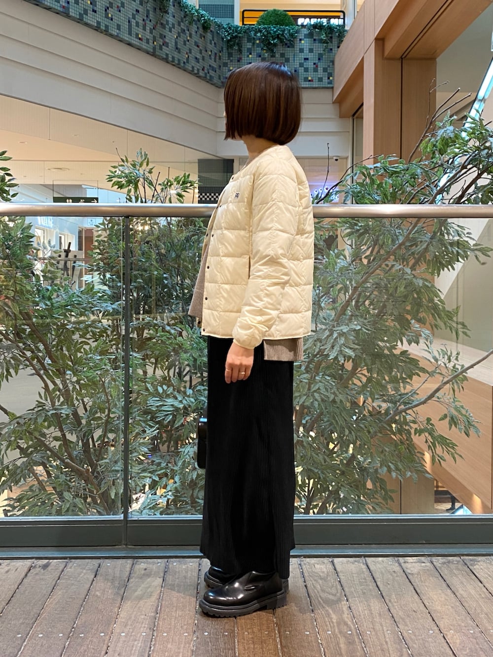 ホワイト系のダウンジャケット/コート、ベージュ系のニット/セーター、ブラック系のTシャツ/カットソーを着用したレディースの冬コーディネートの2枚目の写真