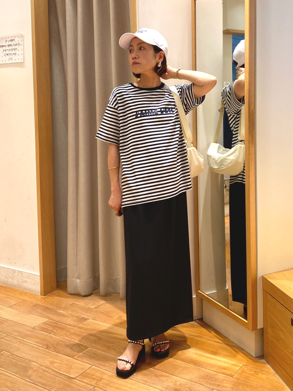 ブラック系のスカート、ホワイト系のTシャツ/カットソー、ホワイト系のショルダーバッグを着用したレディースの夏コーディネートの2枚目の写真