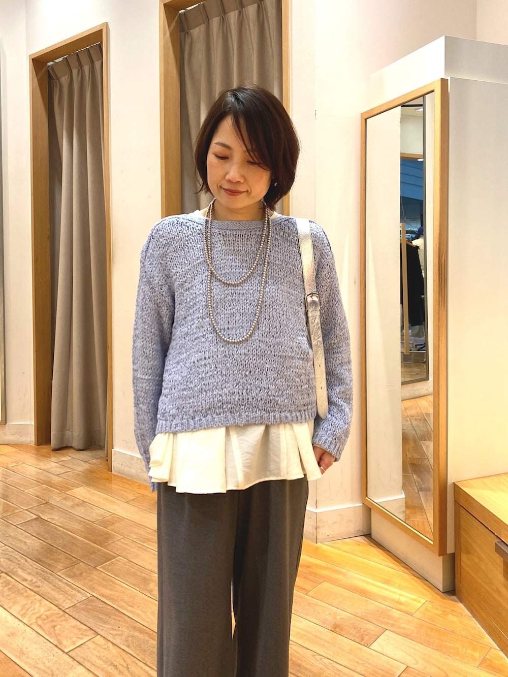 グレー系のその他パンツ、ホワイト系のシャツ/ブラウス、ブルー系のニット/セーターを着用したレディースの春コーディネートの3枚目の写真