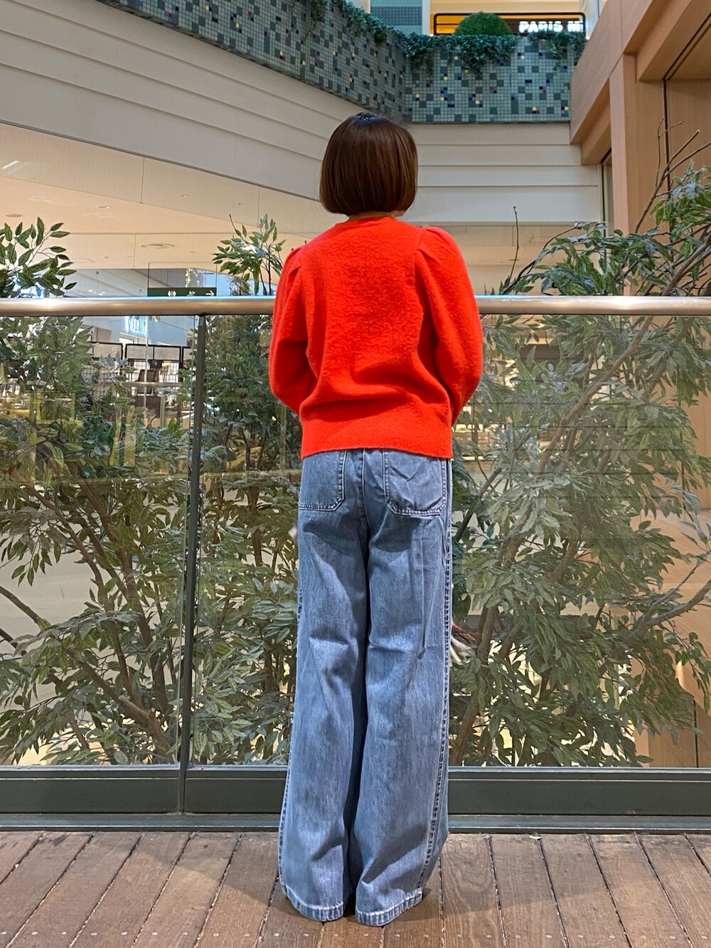 レッド系のニット/セーター、ブルー系のデニムパンツ、ベージュ系のハンドバッグを着用したレディースの冬コーディネートの6枚目の写真