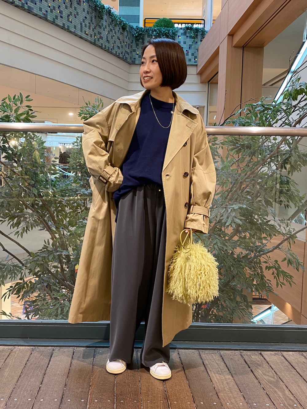 ベージュ系のトレンチコート、ブルー系のニット/セーター、グレー系のその他パンツを着用したレディースの秋コーディネートの2枚目の写真