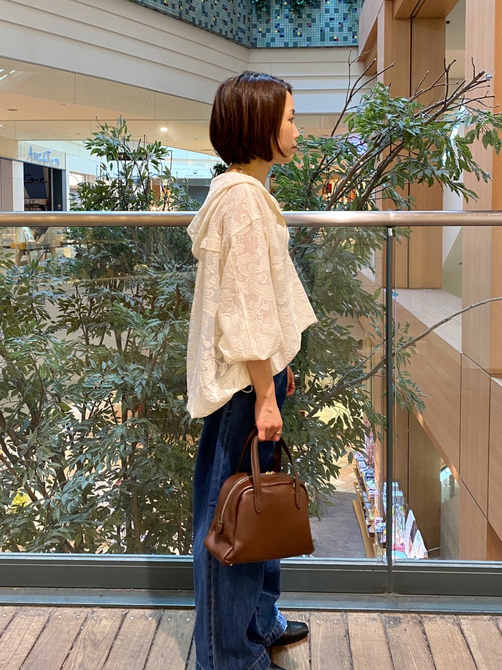 ホワイト系のシャツ/ブラウス、ブルー系のデニムパンツ、ブラウン系のボストンバッグを着用したレディースの秋コーディネートの4枚目の写真