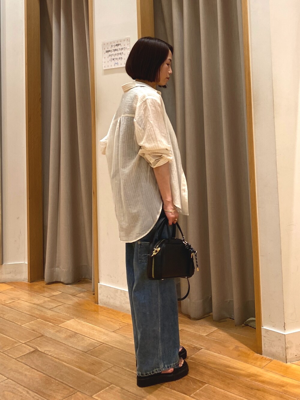 ブルー系のデニムパンツ、ブラック系のショルダーバッグ、ホワイト系のシャツ/ブラウスを着用したレディースの夏コーディネートの6枚目の写真