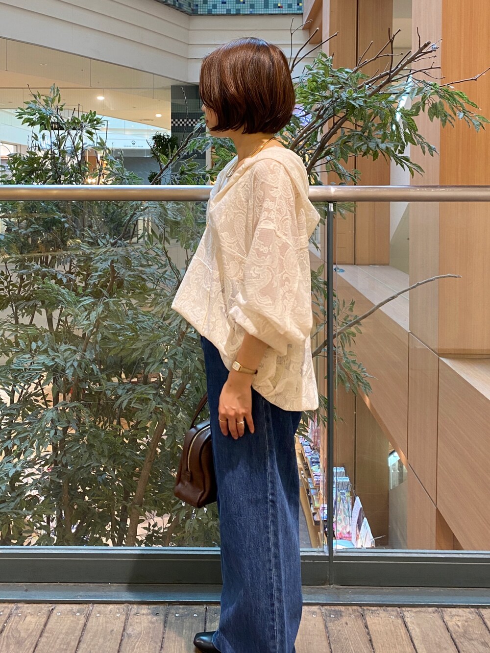 ホワイト系のシャツ/ブラウス、ブルー系のデニムパンツ、ブラウン系のボストンバッグを着用したレディースの秋コーディネートの3枚目の写真