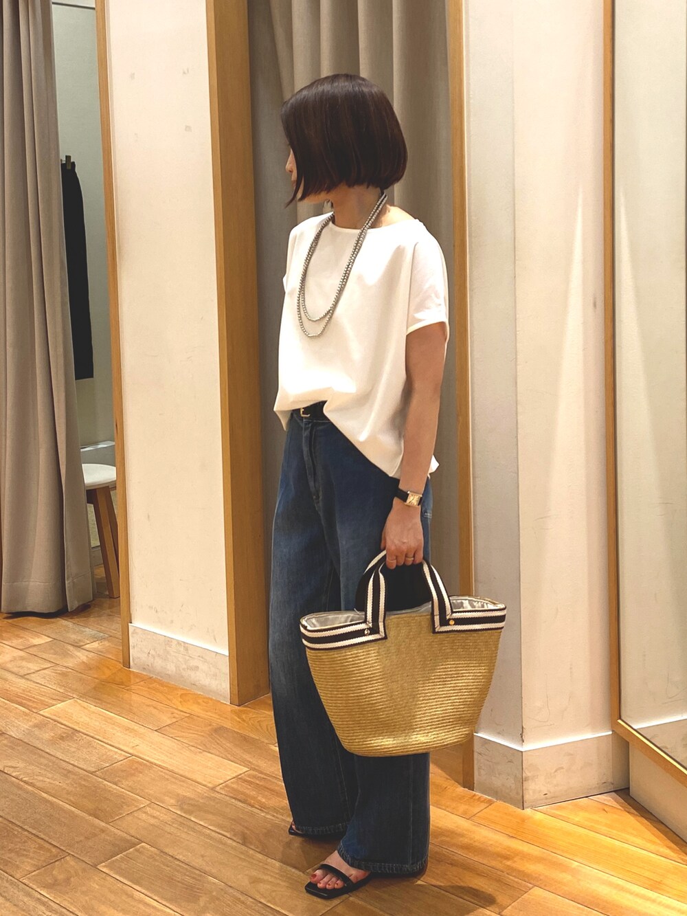 ブルー系のデニムパンツ、ホワイト系のTシャツ/カットソー、ベージュ系のかごバッグを着用したレディースの夏コーディネートの4枚目の写真
