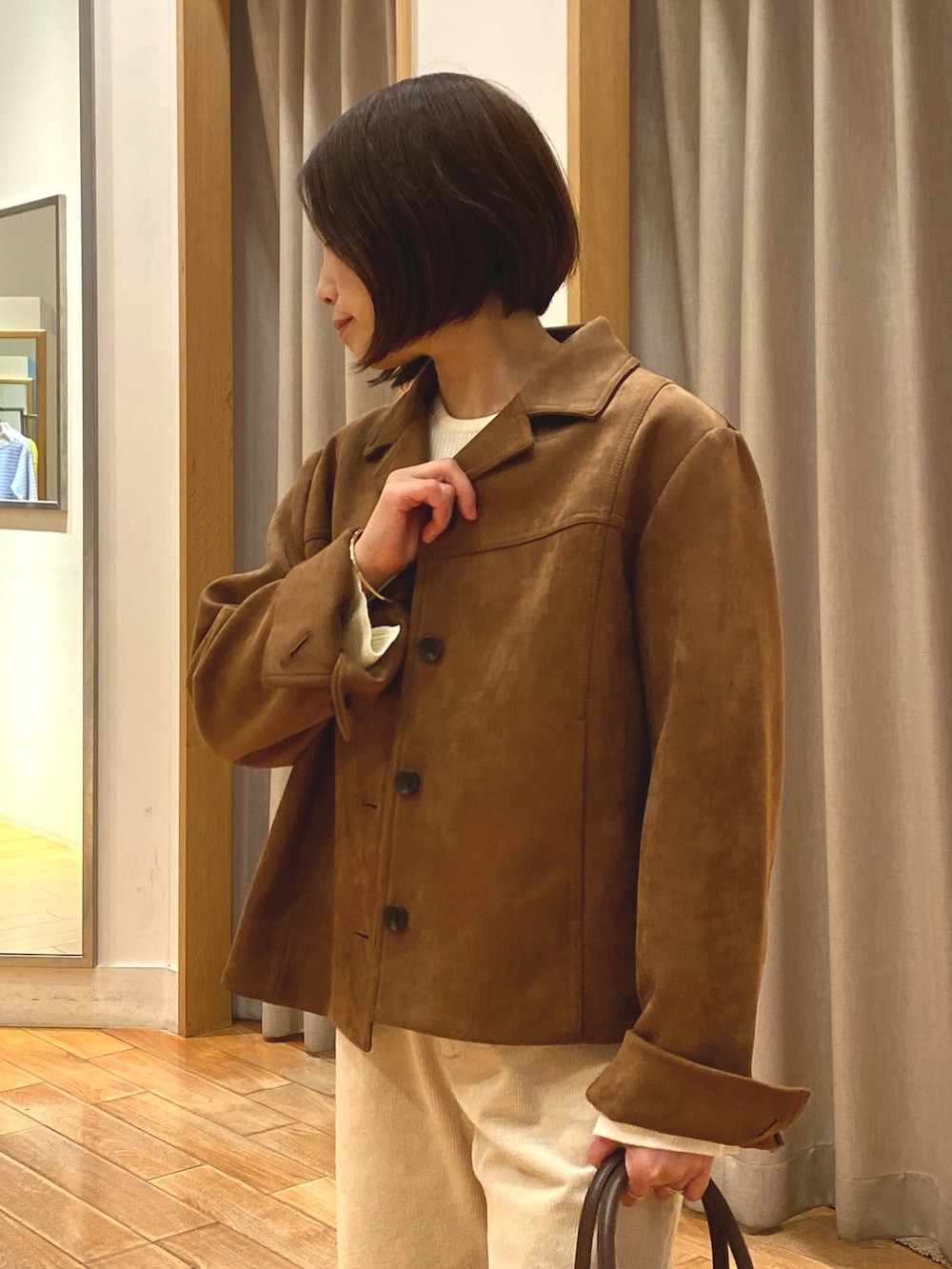 ブラウン系のダウンジャケット/コート、ホワイト系のニット/セーター、ブラウン系のショルダーバッグを着用したレディースの秋コーディネートの6枚目の写真