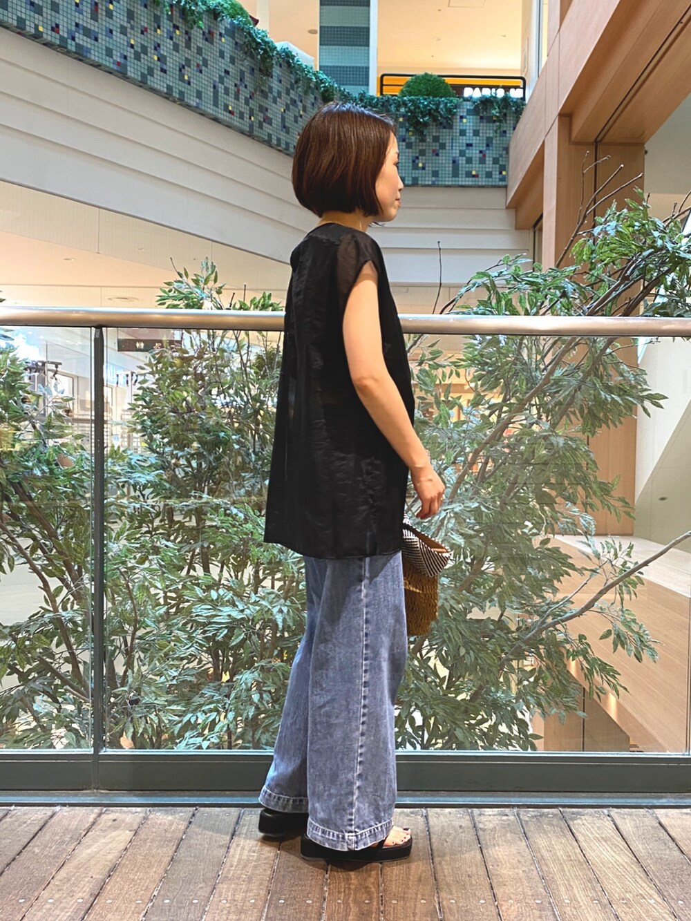 ブラック系のシャツ/ブラウス、ブラウン系のかごバッグ、ブルー系のデニムパンツを着用したレディースの夏コーディネートの4枚目の写真