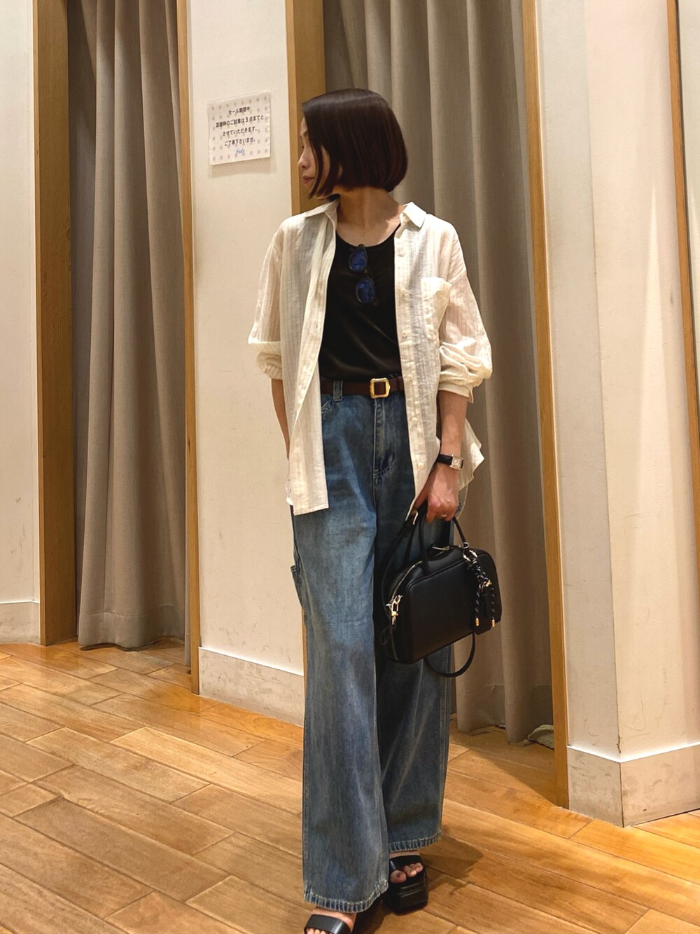 ブルー系のデニムパンツ、ブラック系のショルダーバッグ、ホワイト系のシャツ/ブラウスを着用したレディースの夏コーディネートの2枚目の写真