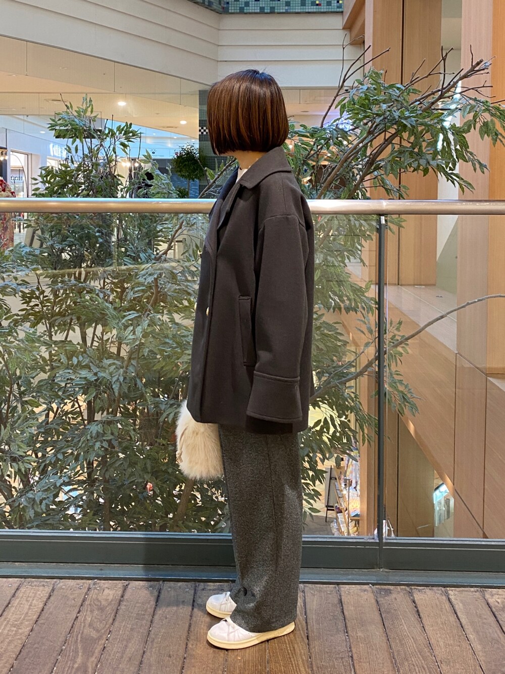 グレー系のピーコート、ホワイト系のその他トップス、グレー系のスラックスを着用したレディースの冬コーディネートの3枚目の写真
