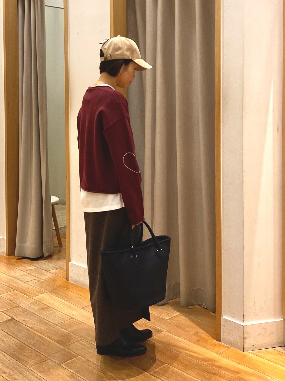 レッド系のニット/セーター、ブラウン系のスカート、ホワイト系のTシャツ/カットソーを着用したレディースの秋コーディネートの5枚目の写真