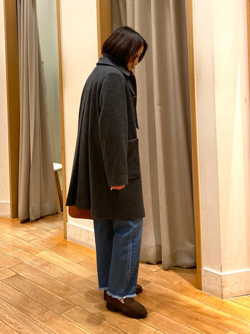 グレー系のダッフルコート、ブルー系のニット/セーター、ブルー系のデニムパンツを着用したレディースの冬コーディネートの5枚目の写真