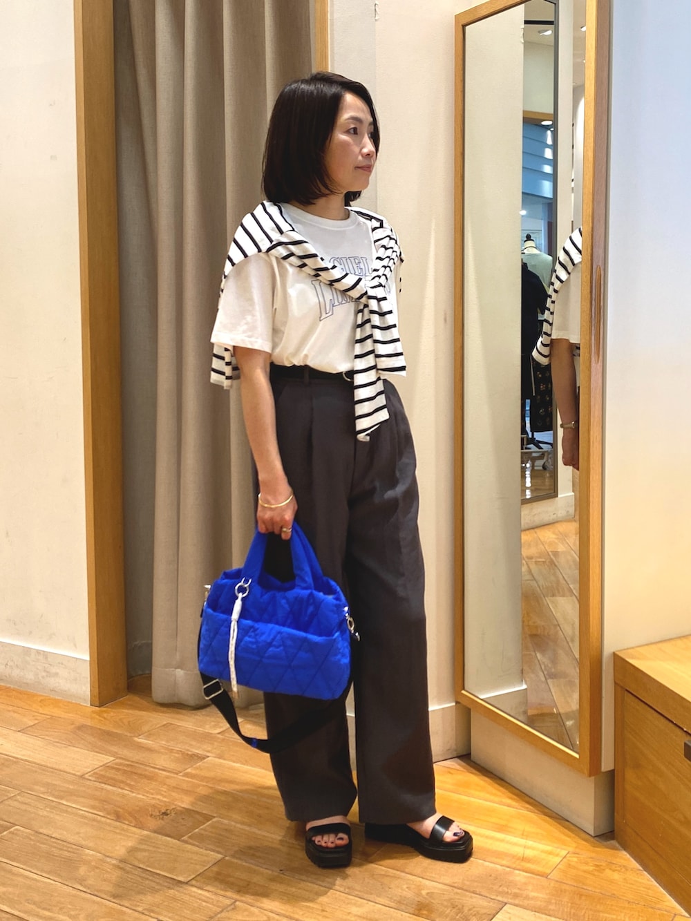 グレー系のスラックス、ブルー系のショルダーバッグ、ホワイト系のTシャツ/カットソーを着用したレディースの夏コーディネートの5枚目の写真