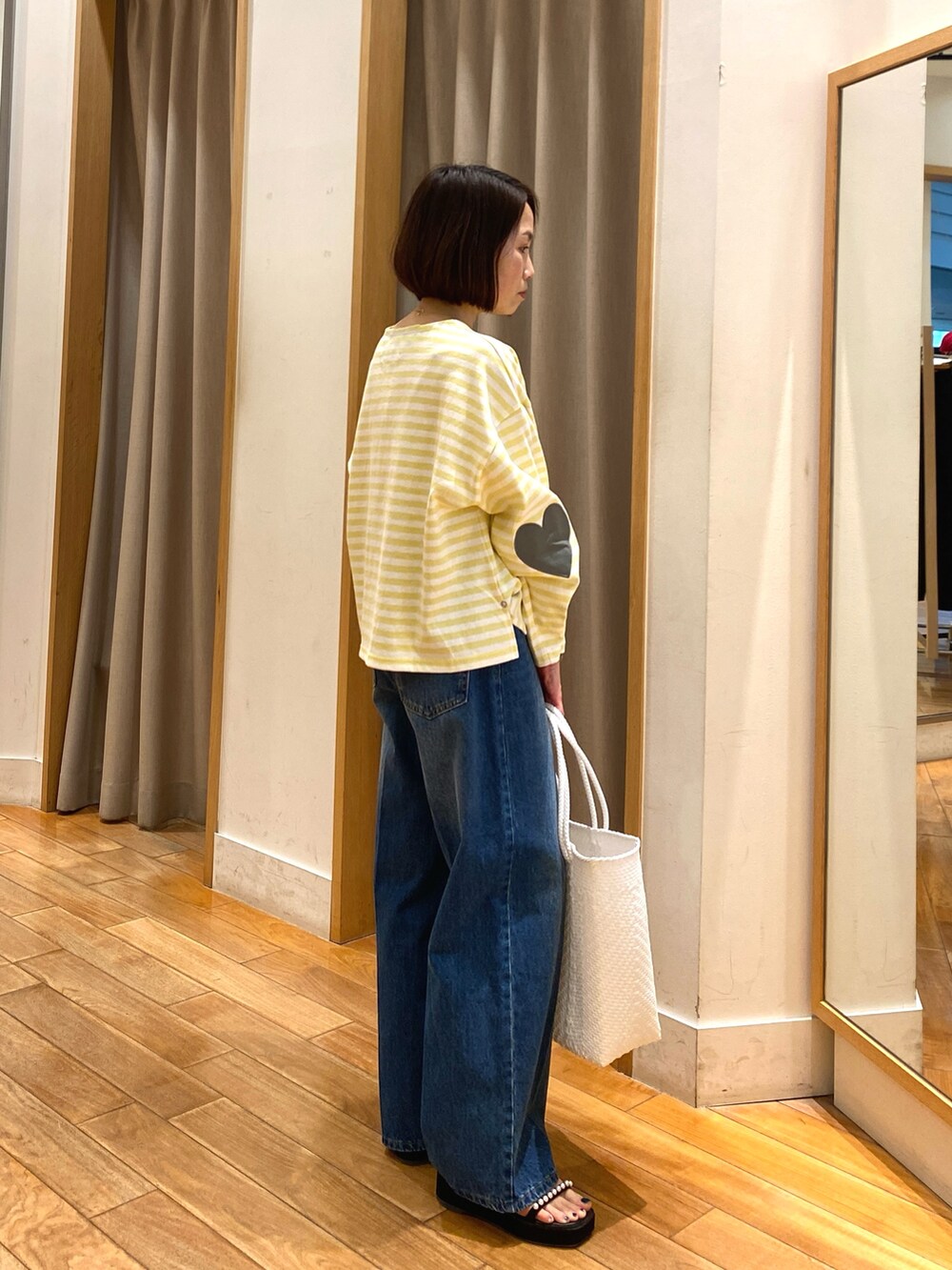 イエロー系のTシャツ/カットソー、ブルー系のデニムパンツ、ホワイト系のかごバッグを着用したレディースの春コーディネートの2枚目の写真