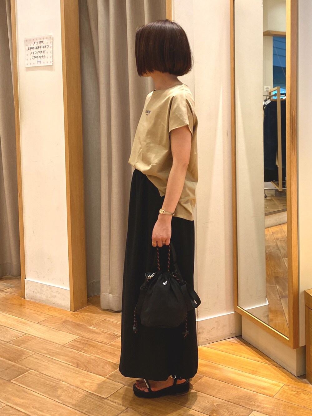 ブラック系のスカート、ブラック系のショルダーバッグ、イエロー系のTシャツ/カットソーを着用したレディースの夏コーディネートの3枚目の写真