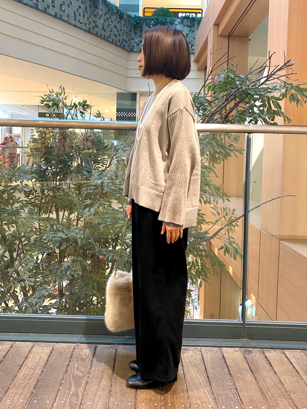 ブラック系のその他パンツ、ベージュ系のハンドバッグ、ベージュ系のニット/セーターを着用したレディースの冬コーディネートの4枚目の写真