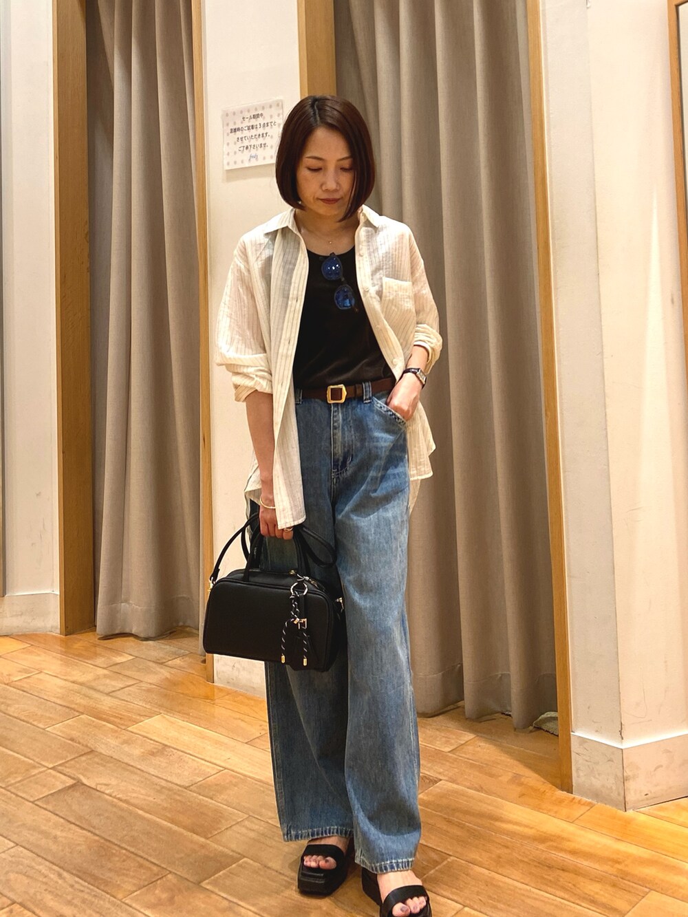 ブルー系のデニムパンツ、ブラック系のショルダーバッグ、ホワイト系のシャツ/ブラウスを着用したレディースの夏コーディネートの3枚目の写真