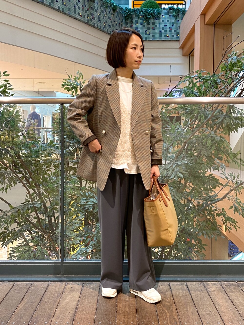 ベージュ系のテーラードジャケット、ホワイト系のベスト、イエロー系のショルダーバッグを着用したレディースの秋コーディネートの3枚目の写真