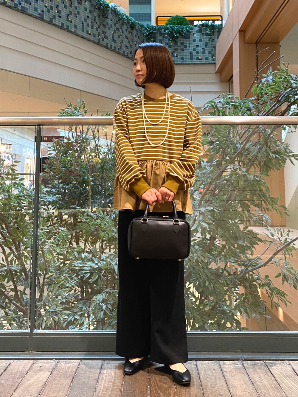 ベージュ系のTシャツ/カットソー、ブラック系のハンドバッグ、ブラック系のその他パンツを着用したレディースの冬コーディネートの2枚目の写真