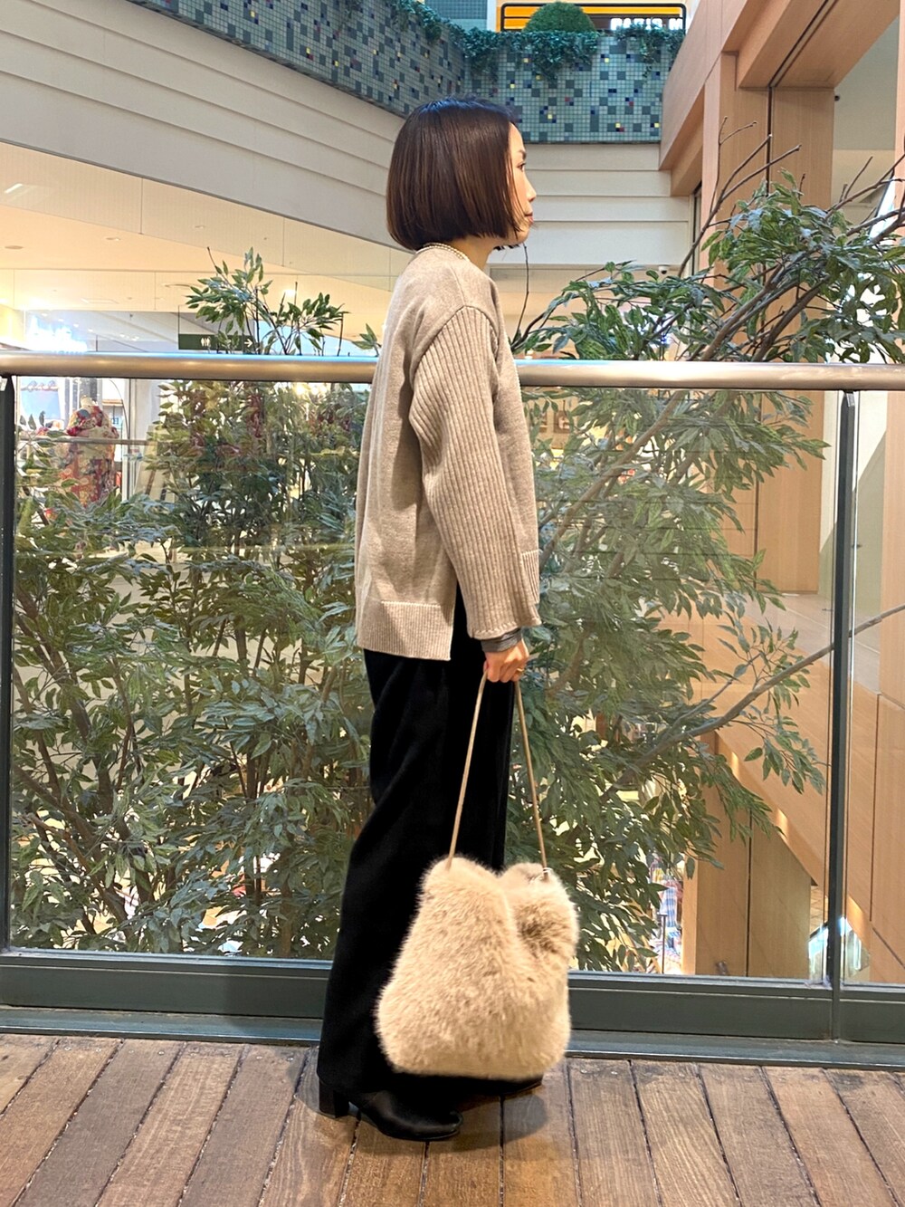 ブラック系のその他パンツ、ベージュ系のハンドバッグ、ベージュ系のニット/セーターを着用したレディースの冬コーディネートの5枚目の写真