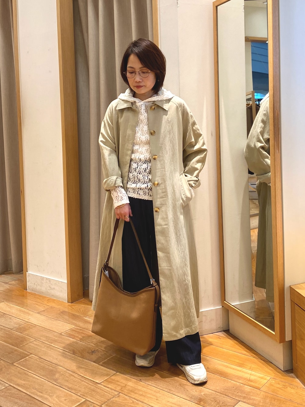 ホワイト系のTシャツ/カットソー、ベージュ系のステンカラーコート、ブラウン系のショルダーバッグを着用したレディースの春コーディネートの2枚目の写真