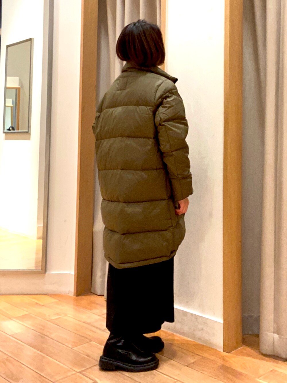 グリーン系のダウンジャケット/コート、ブラック系のスカート、ブラック系のその他トップスを着用したレディースの冬コーディネートの4枚目の写真