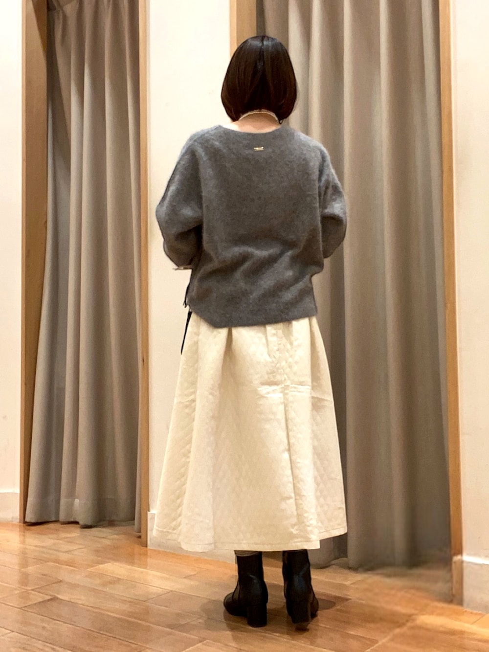 グレー系のニット/セーター、ホワイト系のスカート、ブラック系のハンドバッグを着用したレディースの冬コーディネートの4枚目の写真