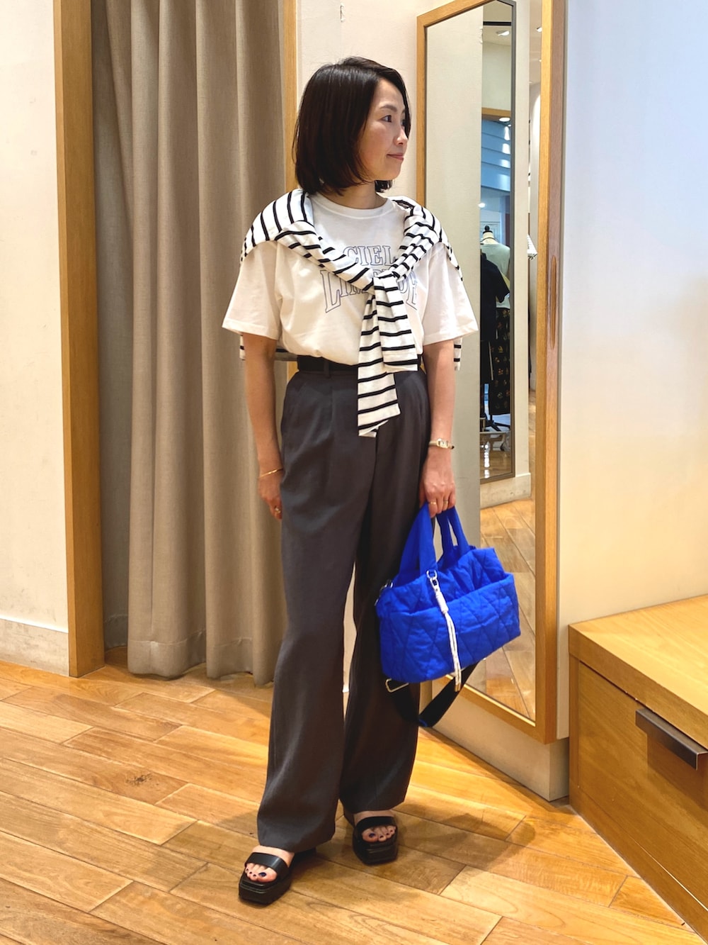 グレー系のスラックス、ブルー系のショルダーバッグ、ホワイト系のTシャツ/カットソーを着用したレディースの夏コーディネートの4枚目の写真